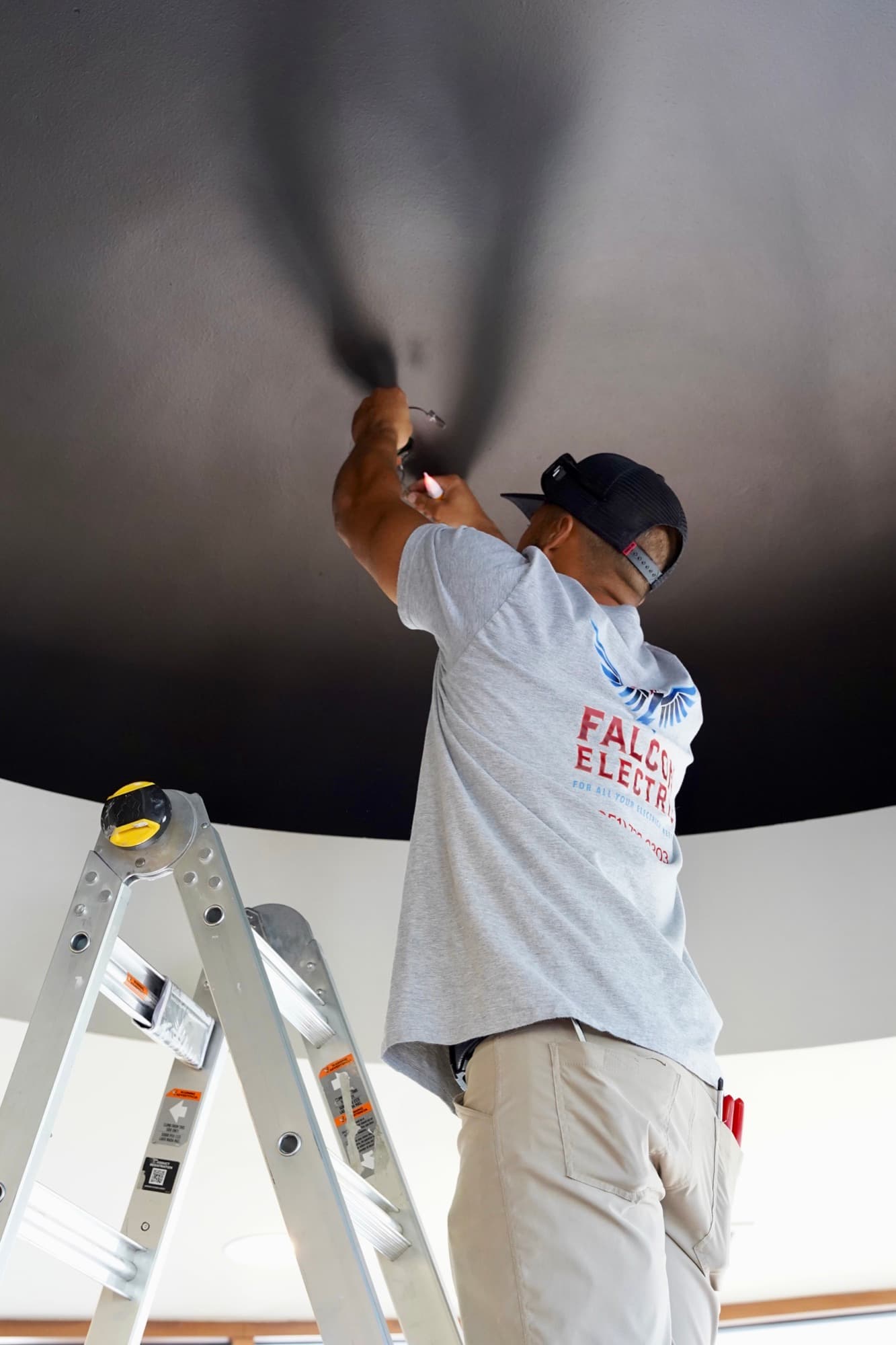 Ean Orchard wiring a ceiling light fixture inside a modern interior