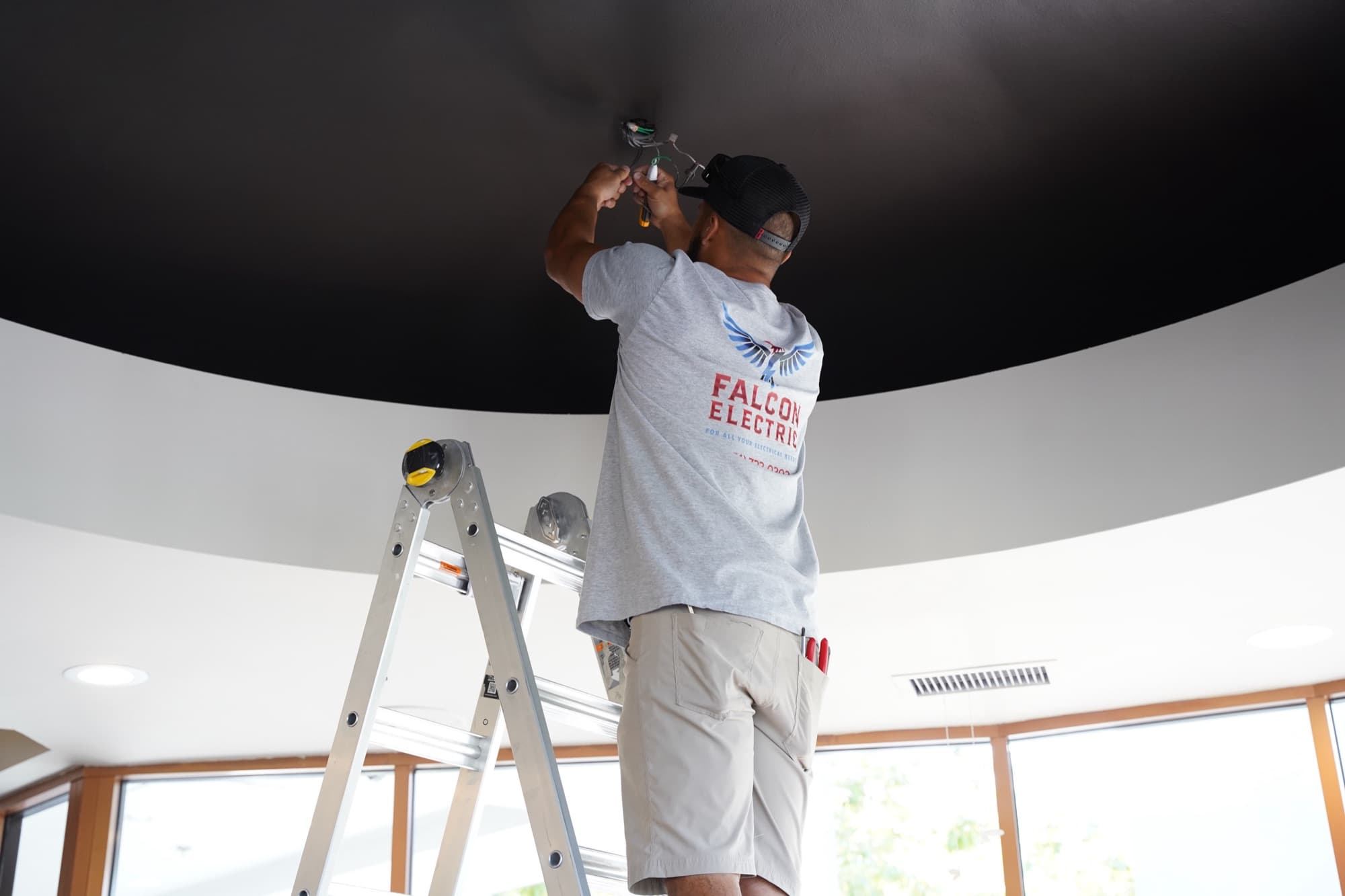 Wide shot of Ean Orchard on a ladder working on a domed ceiling fixture