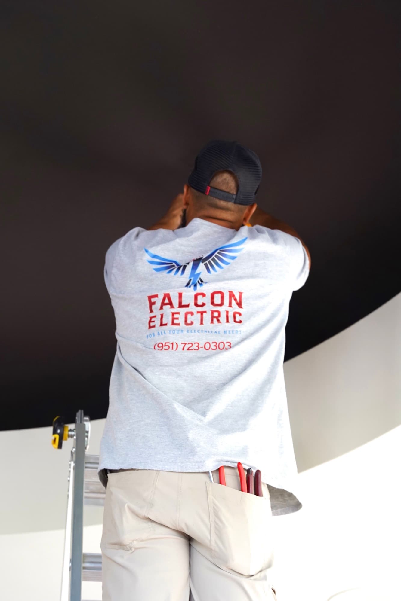 Ean Orchard wearing the Falcon Electric branded shirt while installing a recessed light
