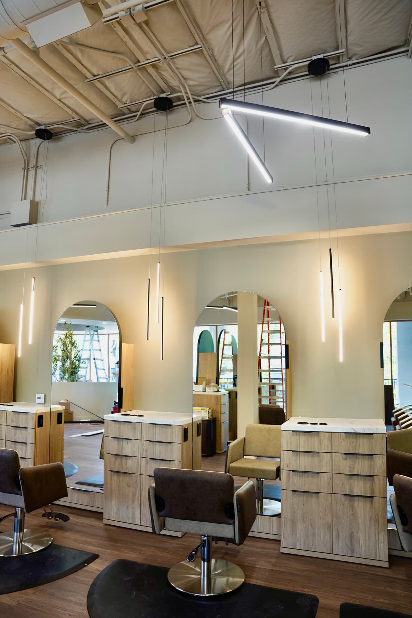 Overhead pendant lighting installation in a high-ceiling salon